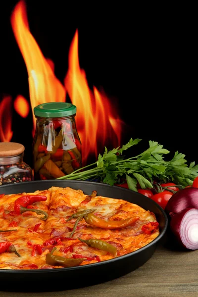 Smakelijke pepperoni pizza in de pan met de groenten op vlam achtergrond — Stockfoto