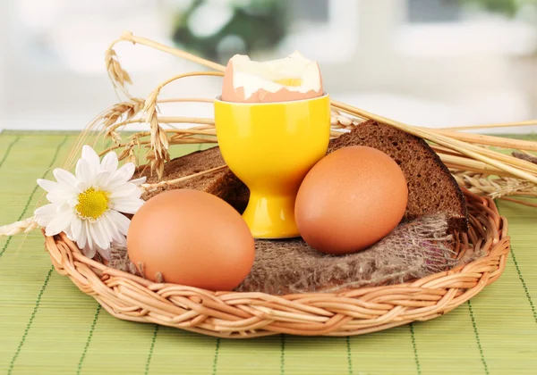 Gekookte eieren op rieten mat op lichte achtergrond — Stockfoto