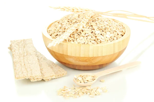 Wooden bowl full of oat flakes with wooden spoon, spikelets and oat biscuits isolated on white — Stock Photo, Image