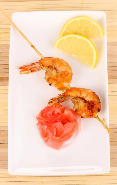 Shrimp skewers on plate with ginger and lemon — Stock Photo, Image