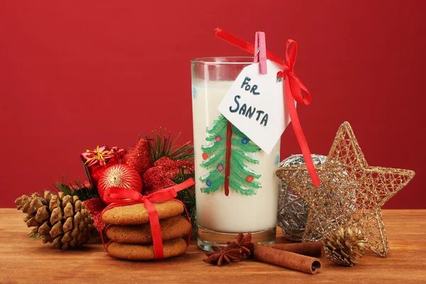 Cookies voor santa: Conceptuele afbeelding van gember koekjes, melk en kerst decoratie op rode achtergrond — Stockfoto