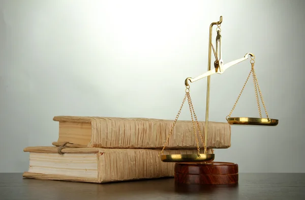 Золотые весы правосудия и книги на сером фоне — стоковое фото