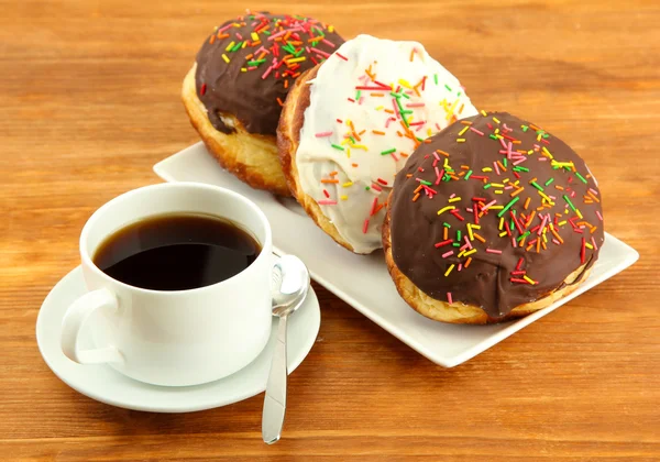 Tasty donuts on color plate on wooden background — Stock Photo, Image