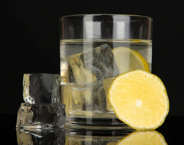 Isbitar i glaset med citron isolerade på svart — Stockfoto