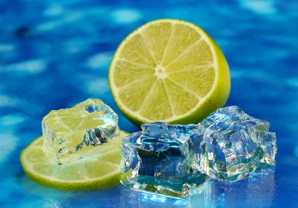 Cubos de hielo con lima sobre fondo azul —  Fotos de Stock