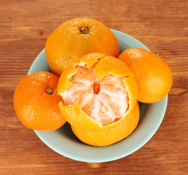 Mandarinas saborosas em tigela de cor no fundo de madeira — Fotografia de Stock