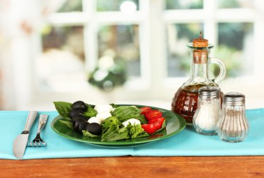 peynir Mozzarella peyniri çatal ve bıçak ahşap masa üzerinde plaka sebze ile