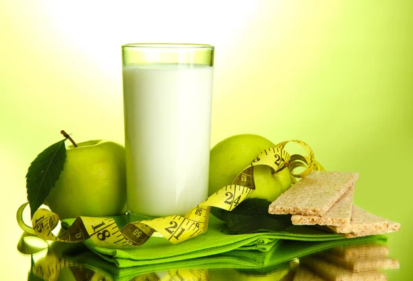 Vaso de kéfir, manzanas, panes fritos y cinta métrica, sobre fondo verde —  Fotos de Stock