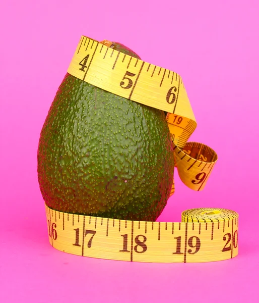 Avocado with measuring tape on pink background — Stock Photo, Image