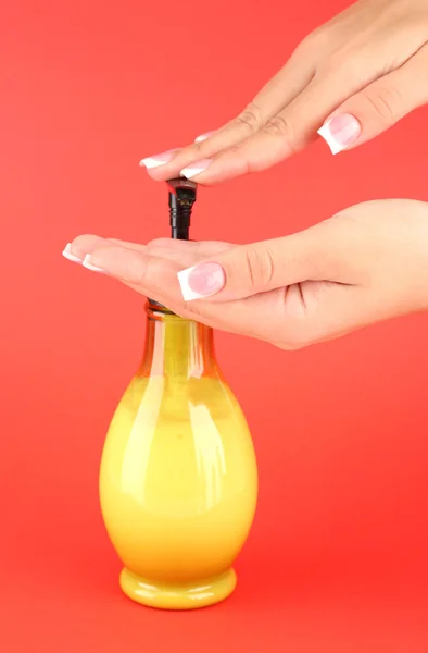 Mujer apretando loción en su mano, sobre fondo rojo de cerca — Foto de Stock