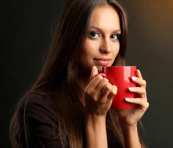 Bela jovem com xícara de café, no fundo marrom — Fotografia de Stock