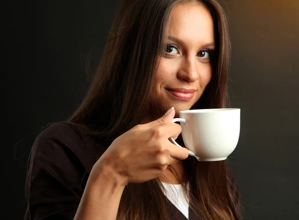 Piękna młoda kobieta z filiżanką kawy na brązowym tle — Zdjęcie stockowe