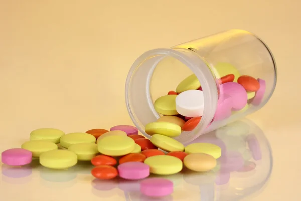 Pills in receptacle on yellow background — Stock Photo, Image