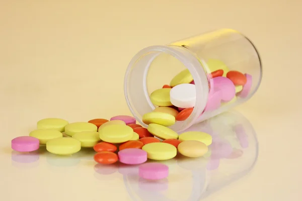 Pills in receptacle on yellow background — Stock Photo, Image