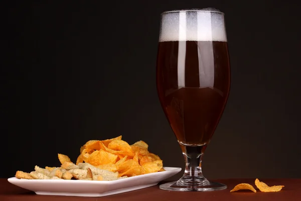 Glas bier met crackers en chips op bruine achtergrond — Stockfoto