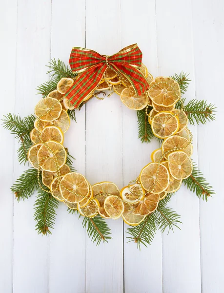 Christmas Krans av torkade citroner med fir tree och båge, på vit trä bakgrund — Stockfoto