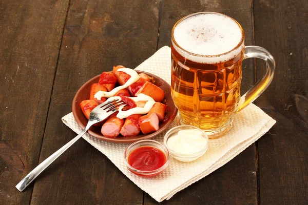 Cerveza y embutidos a la parrilla sobre fondo de madera —  Fotos de Stock