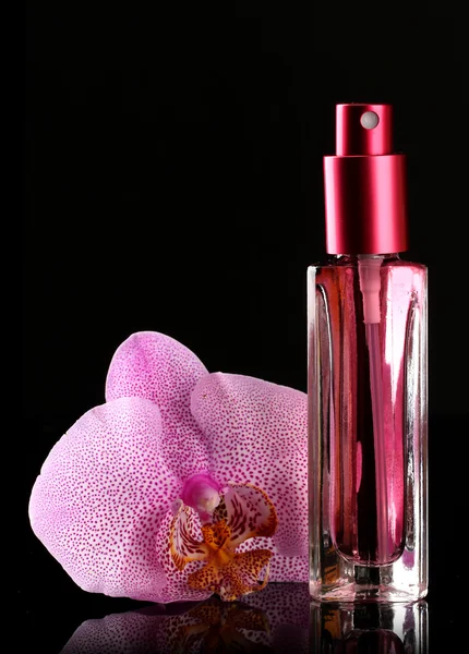 Frauenparfüm in schöner Flasche und Orchideenblume, auf schwarzem Hintergrund — Stockfoto