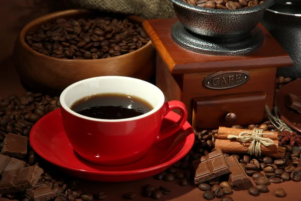 Tasse Kaffee, Kaffeemühle und Kaffeebohnen auf braunem Hintergrund — Stockfoto