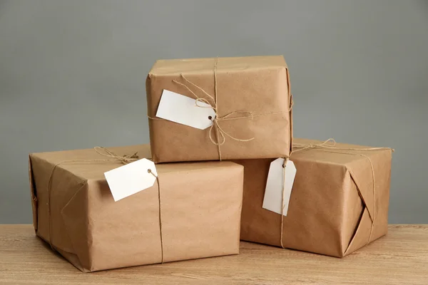 Pacchi scatole con carta kraft, su tavolo di legno su sfondo grigio — Foto Stock