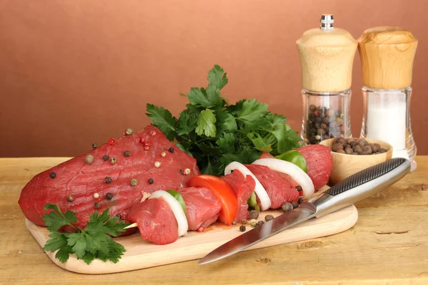 Raw beef meat marinated with herbs and spices on wooden table on brown background — Stock Photo, Image