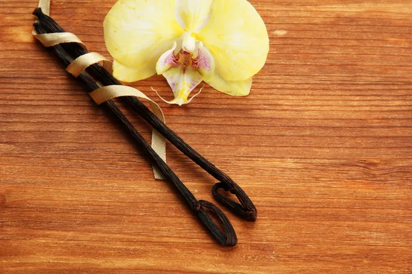 Vanilla pods with flower, on brown wooden background — Stock Photo, Image