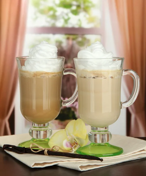 Fragrant coffee latte in glasses cups with vanilla pods, on table in cafe — Stock Photo, Image