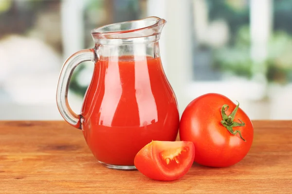 Jarra llena de jugo de tomate, sobre mesa de madera sobre fondo brillante —  Fotos de Stock