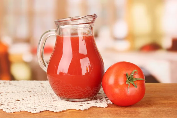 Pełny dzbanek soku pomidorowego, na drewnianym stole na jasnym tle — Zdjęcie stockowe