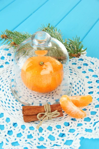 Tangerine on saucer under glass cover on blue background — Stock Photo, Image