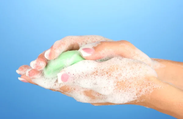 Mani di donna in sapone, su sfondo blu primo piano — Foto Stock