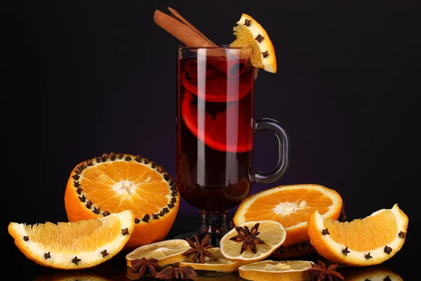Duftender Glühwein im Glas mit Gewürzen und Orangen auf violettem Hintergrund — Stockfoto