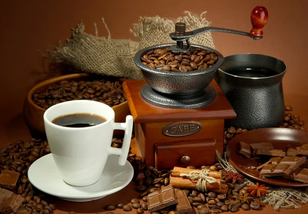 Šálek kávy, mlýnek, Turek a kávová zrna na hnědé pozadí — Stock fotografie