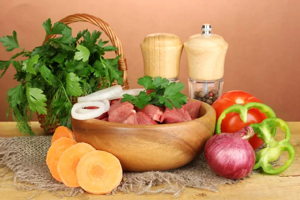 Ruwe rundvlees met kruiden en specerijen op houten tafel op bruine achtergrond — Stockfoto