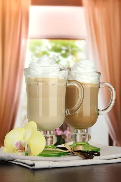 Café con leche fragante en vasos tazas con vainas de vainilla, en la mesa en la cafetería —  Fotos de Stock