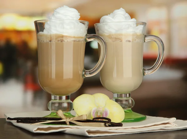 Geurende koffie latte in glazen bekers met vanillestokjes, op tafel in café — Stockfoto