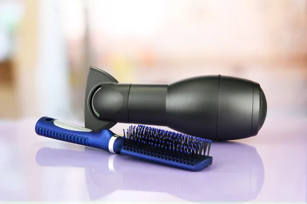 Hair dryer and comb brush, on table in beauty salon — Stock Photo, Image