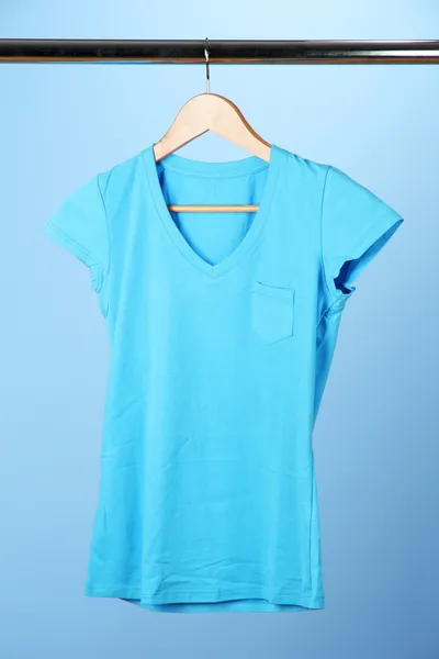 T-shirt on wooden hanger, on blue background — Stock Photo, Image