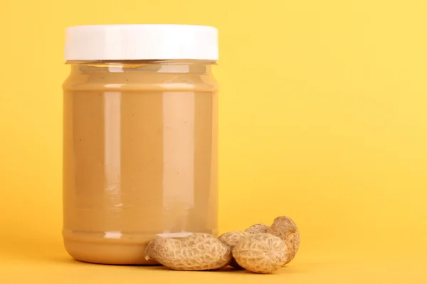 Delicious peanut butter in jar of peanut near on yellow background — Stock Photo, Image