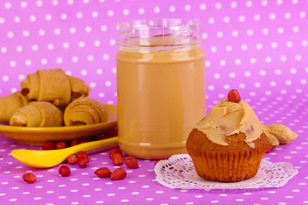 Delicious peanut butter with cookies on purple background with polka dots — Stock Photo, Image