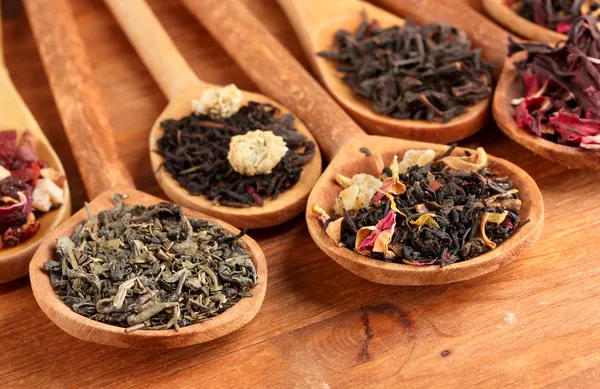 Auswahl an trockenem Tee in Löffeln, auf Holzgrund — Stockfoto