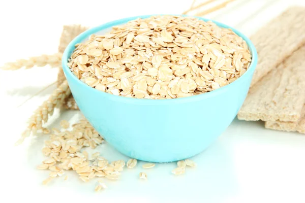 Blue bowl full of oat flakes with spikelets and oat biscuits isolated on white — Stock Photo, Image