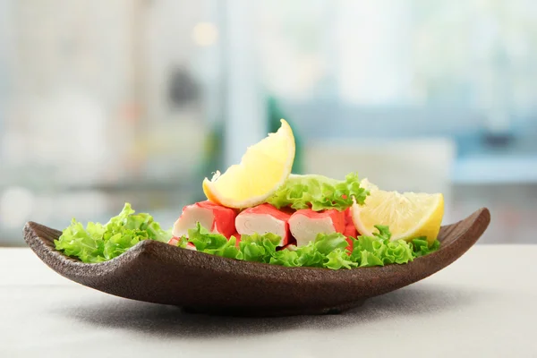 Crab sticks with lettuce leaves and lemon on plate, close up — Stock Photo, Image