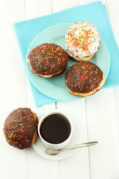 Tasty donuts on color plate on light wooden background — Stock Photo, Image