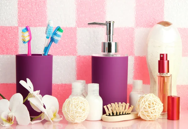 Accesorios de baño en el estante en el baño sobre fondo de pared de baldosas rosa —  Fotos de Stock