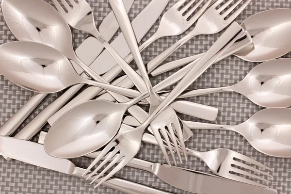 Forks, knifes and spoons on grey mat close-up — Stock Photo, Image