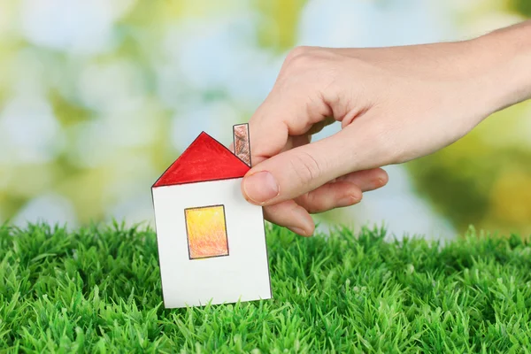 Female hand holding paper house on green background, close up — Stock Photo, Image