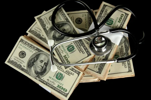 Concept de coût des soins de santé : stéthoscope et dollars isolés sur noir — Photo