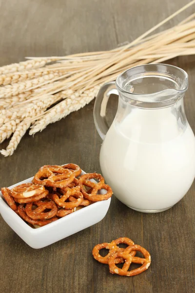 Ahşap masa yakın çekim üzerinde beyaz kase ve süt kabı içinde lezzetli simit — Stok fotoğraf