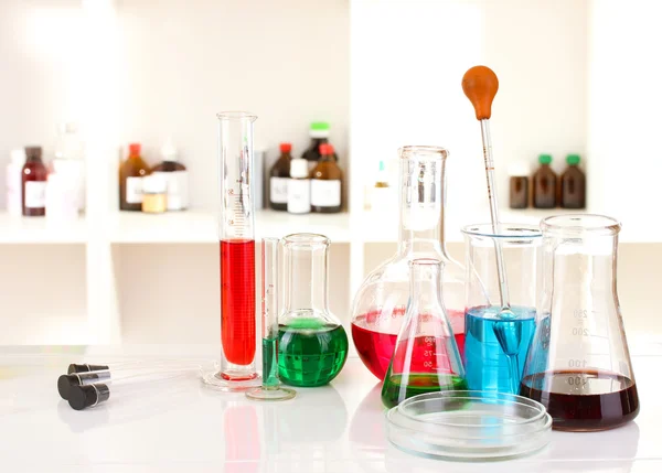 Different laboratory glassware with color liquid on laboratory background — Stock Photo, Image